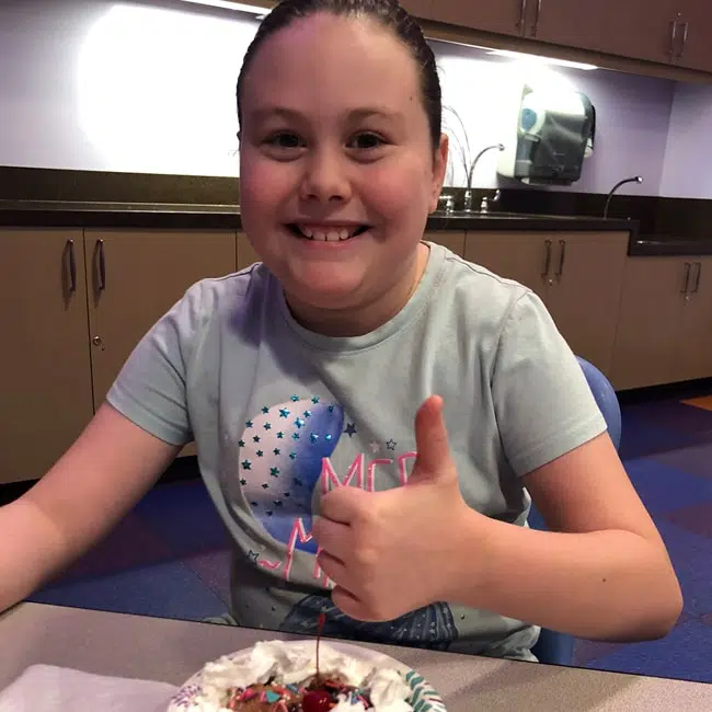 Child giving the thumbs up sitting in the events room