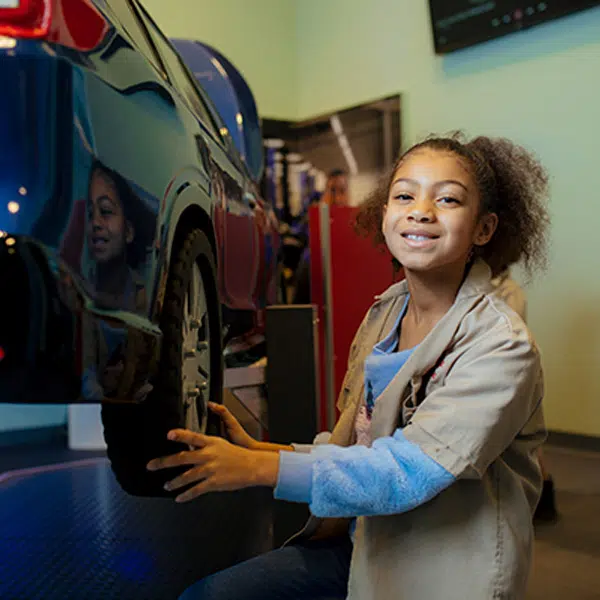 A young girl holding a small tire from a 1/3 model car