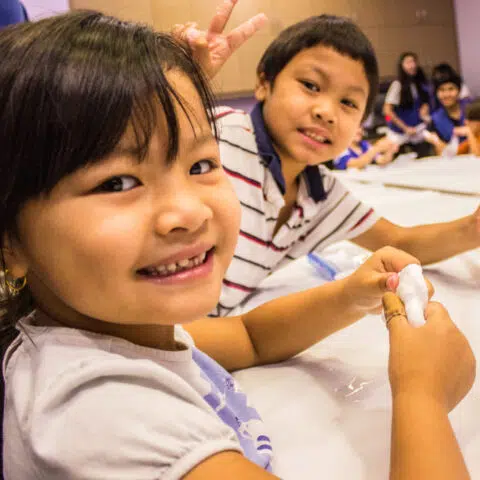 2 children holding slime at a table and posing for a photo at a Discovery Children's Museum summer camp