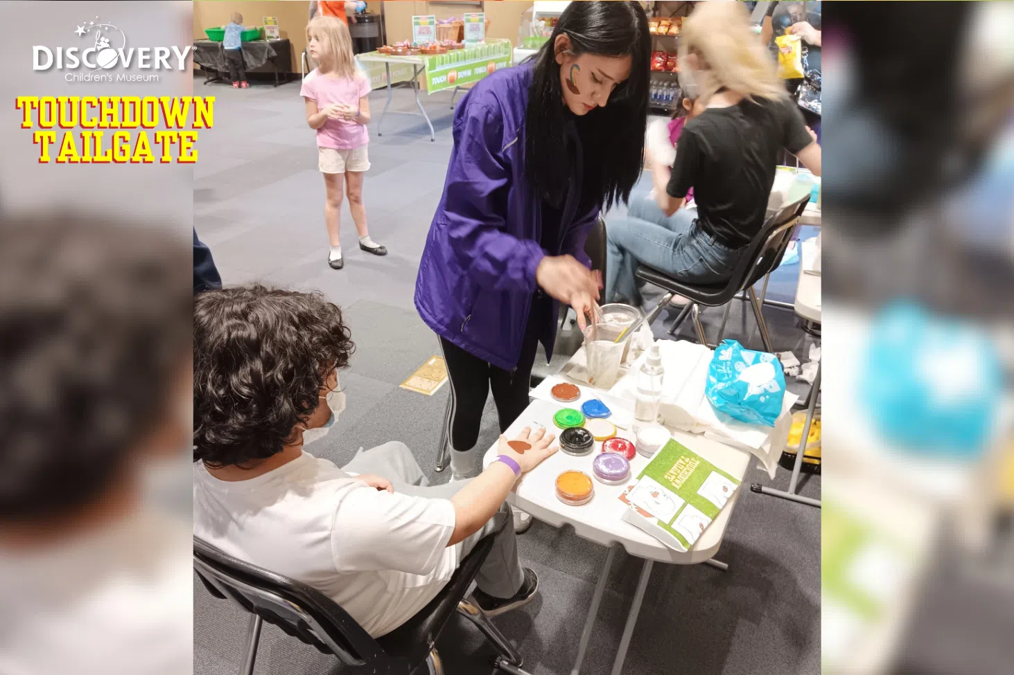 A face painter painting on a child's hand at the Discovery Children's Museum